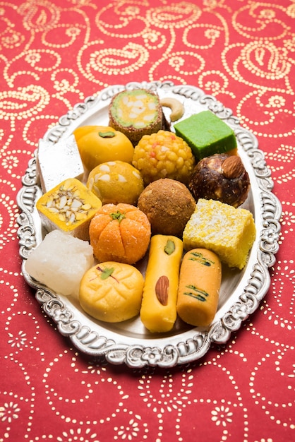 Indian sweets served in silver or wooden plate. variety of Peda, burfi, laddu in decorative plate, selective focus