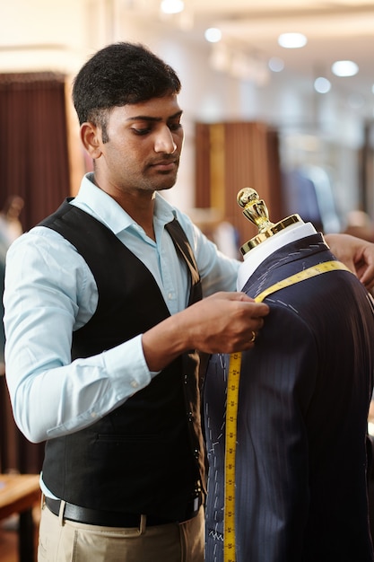 Premium Photo | Indian tailor measuring distance between shoulders of ...