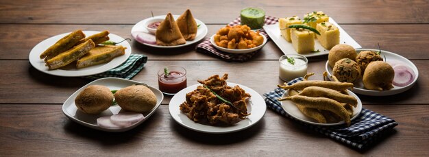 Indian Tea time snacks  in group includes Veg Samosa, Kachori, kachaudi, aloo bonda, khaman dhokla, bread, onion,chilli and moong pakora, pakoda, bhaji, bhajji,Bhajiya,bajji with sauces