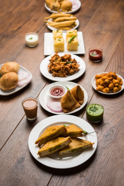 Indian Tea time snacks  in group includes Veg Samosa, Kachori, kachaudi, aloo bonda, khaman dhokla, bread, onion,chilli and moong pakora, pakoda, bhaji, bhajji,Bhajiya,bajji with sauces