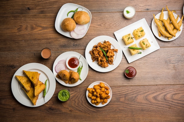 Foto gli snack indiani dell'ora del tè in gruppo includono veg samosa, kachori, kachaudi, aloo bonda, khaman dhokla, pane, cipolla, peperoncino e moong pakora, pakoda, bhaji, bhajji, bhajiya, bajji con salse