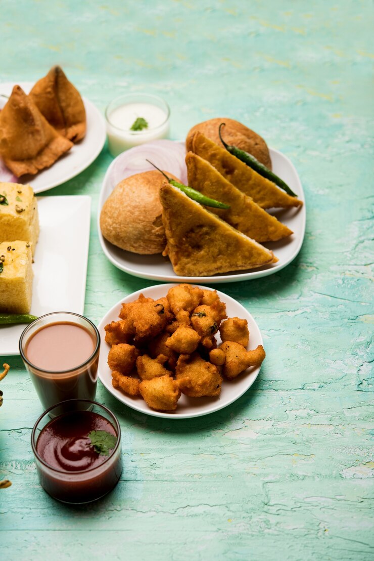 Photo indian tea time snacks  in group includes veg samosa, kachori, kachaudi, aloo bonda, khaman dhokla, bread, onion,chilli and moong pakora, pakoda, bhaji, bhajji,bhajiya,bajji with sauces