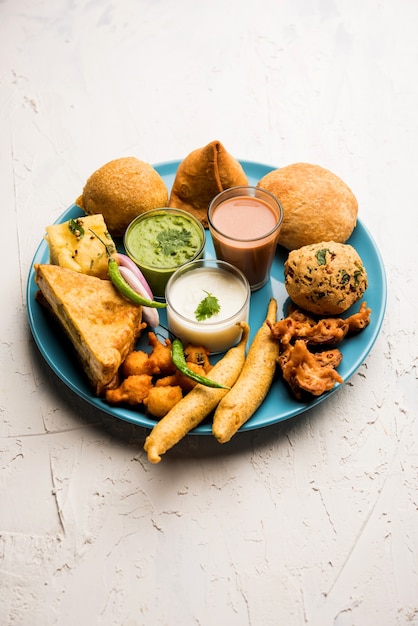 Indian tea time snacks in group includes veg samosa, kachori, kachaudi, aloo bonda, khaman dhokla, bread, onion,chilli and moong pakora, pakoda, bhaji, bhajji,bhajiya,bajji with sauces