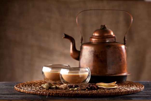 Indian tea with milk and spices masala chai in a copper kettle and cups