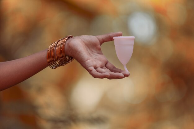 再利用可能なシリコンMenstrualcup、屋外の画像を持っているインドの10代の少女の手