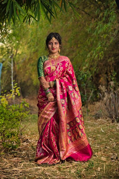 写真 インドの伝統的なサリーを着た美しい若い女の子が公園の外でポーズをとっている