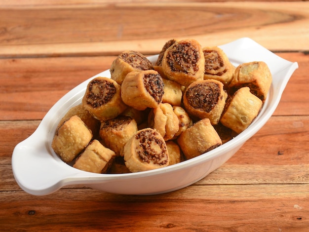 Indian Traditional Tea Time Snack Bhakarwadi Also Know as Bakarwadi Bakarvadi or Bakar Wadi served over a white plate on a rustic wooden background selective focus