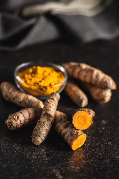 Foto radice e polvere di curcuma indiana spezie di curcuma curcuma macinata su tavolo nero