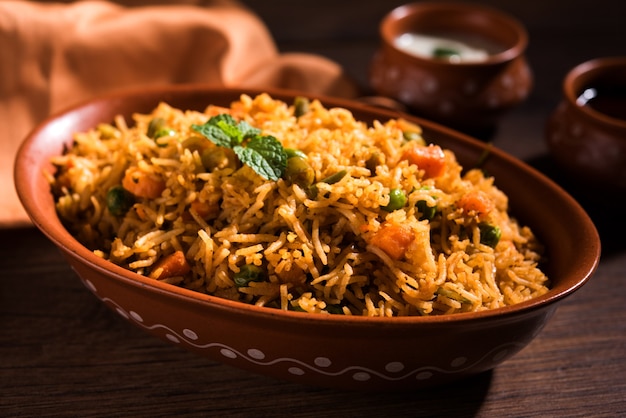 Indian Vegetable Pulav or Biryani made using Basmati Rice, served in terracotta bowl. selective focus