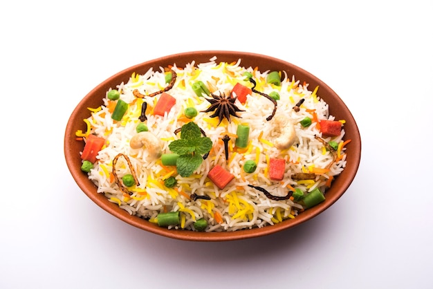 Индийский овощной пулав или бирьяни, приготовленный из риса басмати, подается в терракотовой миске. выборочный фокус