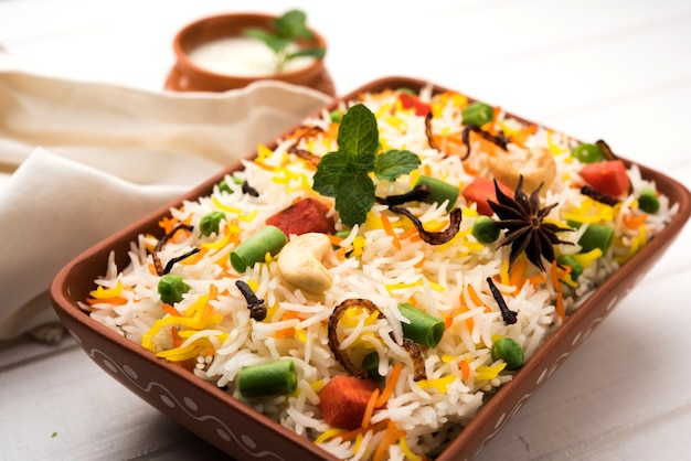 Indian Vegetable Pulav or Biryani made using Basmati Rice, served in terracotta bowl. selective focus