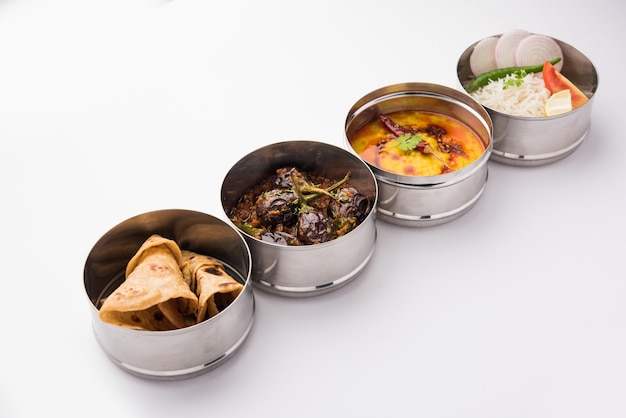 Indian vegetarian Lunch Box or Tiffin made up of stainless steel for office or workplace, includes Dal Fry, Baingan Masala, Rice with chapati and salad