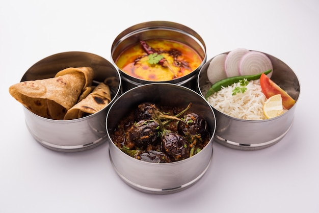 Indian vegetarian Lunch Box or Tiffin made up of stainless steel for office or workplace, includes Dal Fry, Baingan Masala, Rice with chapati and salad