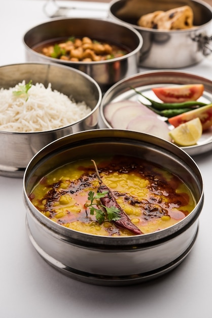 Indian vegetarian Lunch Box or Tiffin made up of stainless steel for office or workplace, includes Dal Fry, Chole Masala, Rice with chapati and salad