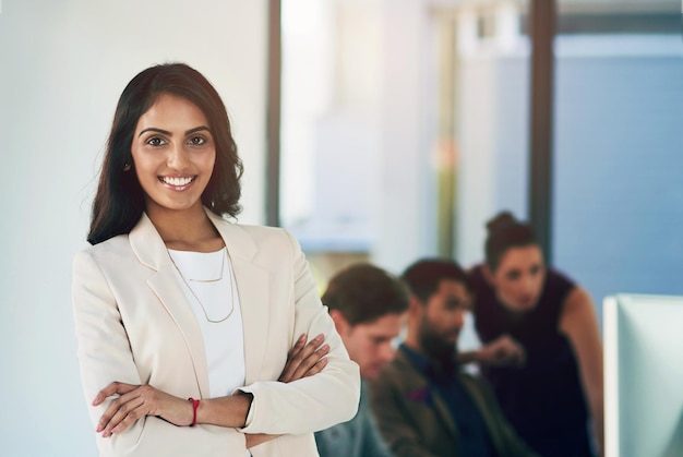 indian woman business and portrait with arms crossed in office with colleagues professional or computer female person face and tech startup as website software or game design confidence or smile