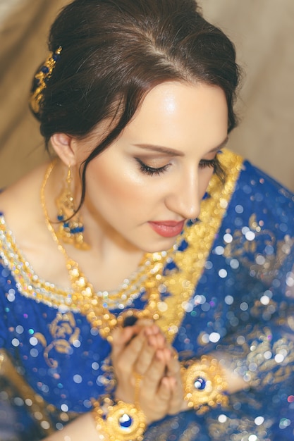 Indian woman cosplay. Young beautiful woman in blue indian sari dress closeup on the multicolored brown background