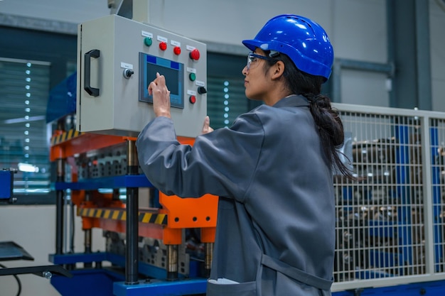 indian woman engineer with a blue helmet and safety goggles operating a control panel controlling