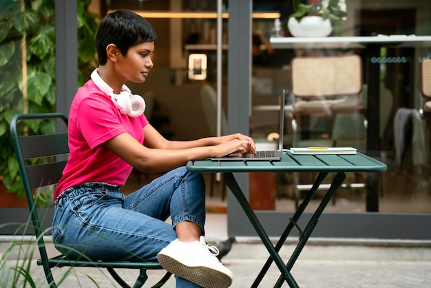Индийская женщина-фрилансер, использующая портативный компьютер, печатающая онлайн, сидя на рабочем месте