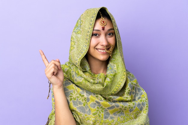 Indian woman isolated on purple background happy and pointing up