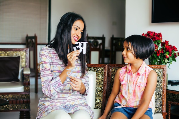 Indian woman teaching her daughter to recognize Hindi alphabets