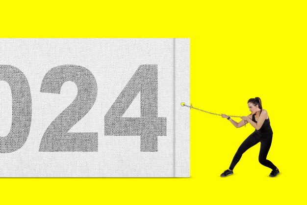 Indian woman wearing sportswear pulling 2023 new year numbers on a banner