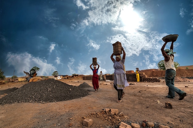 Indian workers carrying bricks on their heads to the kiln in the factory.