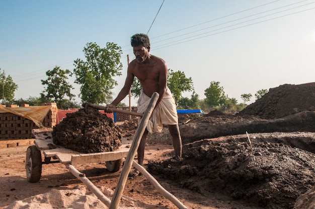 Indian workers processing and carrying clay in the brick factory