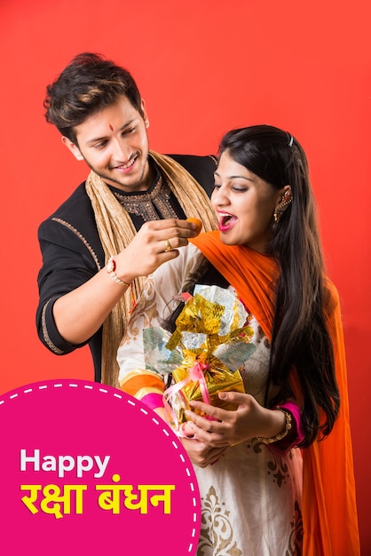 Indian young brother and sister celebrating Raksha Bandhan or Rakhi festival or on Bhai dooj or Bhau-Beej with Poja Thali, sweets, gifts or taking selfie pictures