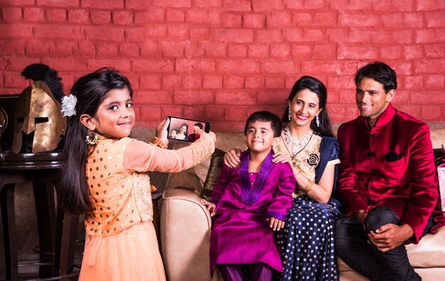 Indian young family taking selfie or self photograph at home with gift boxes on Diwali festival night.