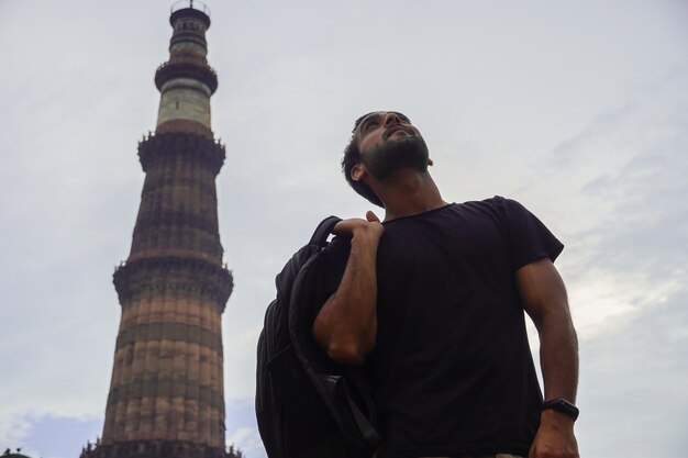 Photo indian young handsome man at historical palace qutub minar travel in india image