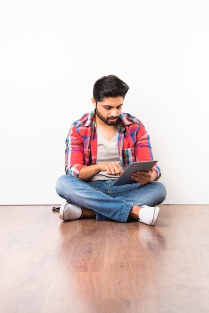 Indian young man using wireless tablet computer for online meeting, video call or presenting empty screen