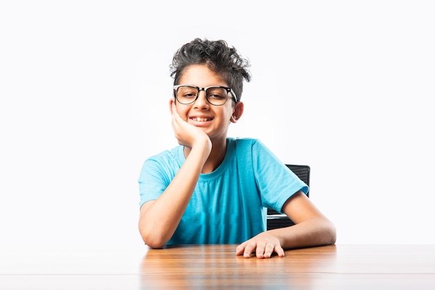 Indiase Aziatische jongen of mannelijk kind zittend aan tafel of bureau, kijkend naar cemara, denkend of iets wijzend