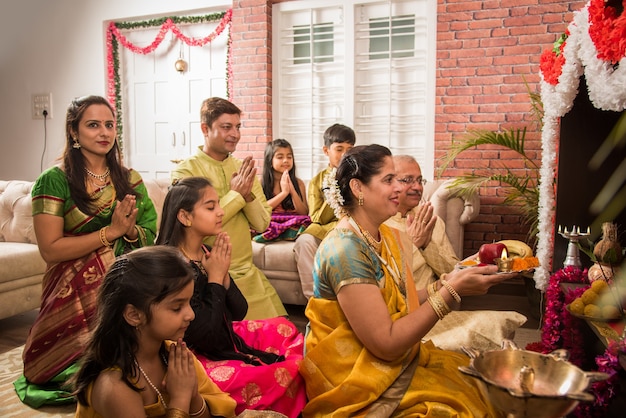 Indiase Aziatische slimme familie die Ganesh puja of Aarti thuis uitvoert terwijl ze traditionele kleding draagt