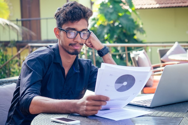Indiase Aziatische student studeert freelancer werken met een laptop op het strand zomercafé freelance en remote werkzakenman op veranda balkon