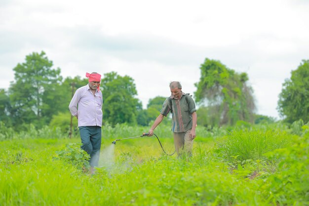 Indiase boer en arbeid sproeien van pesticiden op het veld