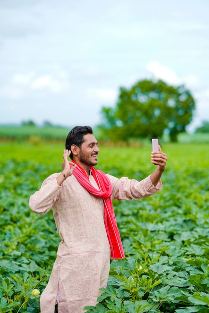 Indiase boer met smartphone op landbouwveld.