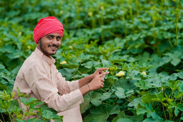 Indiase boer met smartphone op landbouwveld.
