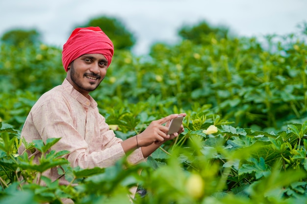 Indiase boer met smartphone op landbouwveld.