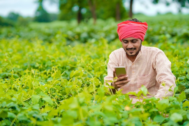 Indiase boer met smartphone op landbouwveld.