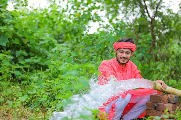 Indiase boer met waterstroom uit pijp op veld