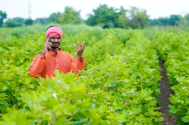 Indiase boer praten op smartphone op landbouwveld