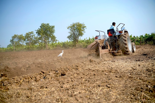 Indiase boer werken met tractor op landbouwgebied.