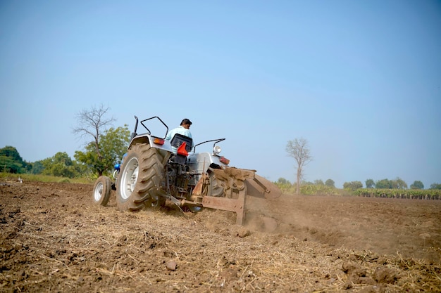 Indiase boer werken met tractor op landbouwgebied.