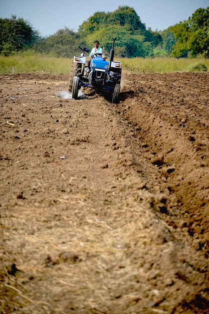 Indiase boer werken met tractor op landbouwgebied.