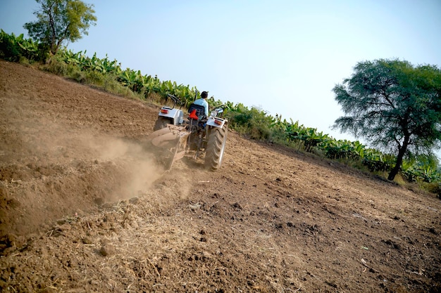 Indiase boer werken met tractor op landbouwgebied.