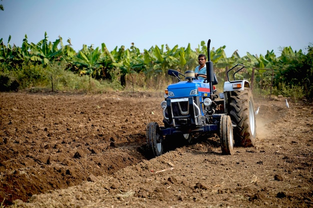 Indiase boer werken met tractor op landbouwgebied.