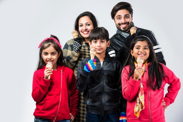 Indiase familie die ijs eet in warme kleren op witte achtergrond