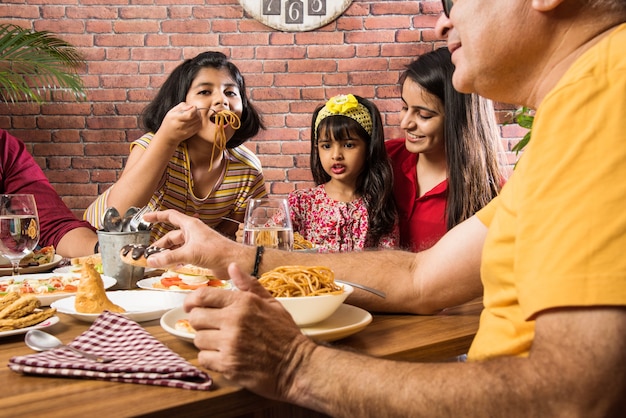 Indiase familie eten aan de eettafel thuis of in een restaurant samen eten