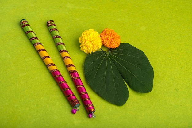 Indiase festival Dussehra en Navratri met gouden blad Bauhinia racemosa en marigold bloemen met Dandiya stokken op een groene achtergrond