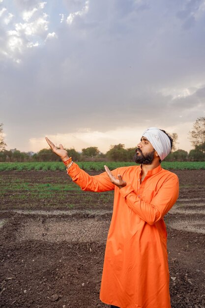 Foto indiase jonge boer die op een landbouwveld staat